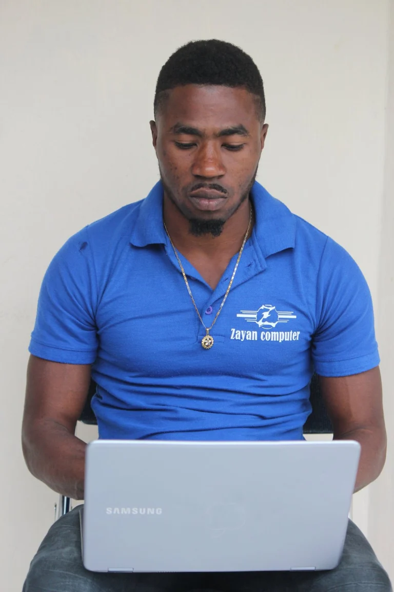 Homme en polo bleu Zayan travaillant sur un ordinateur portable